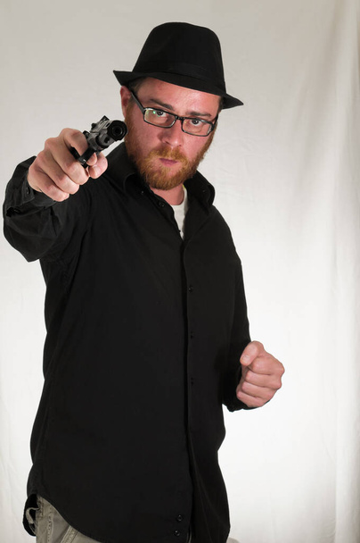 Schwarz gekleideter junger Mann mit Pistole - Foto, Bild