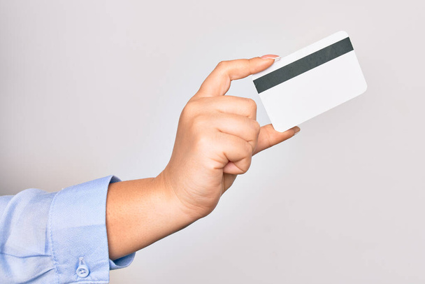 Hand einer kaukasischen jungen Frau mit Kreditkarte vor isoliertem weißen Hintergrund - Foto, Bild