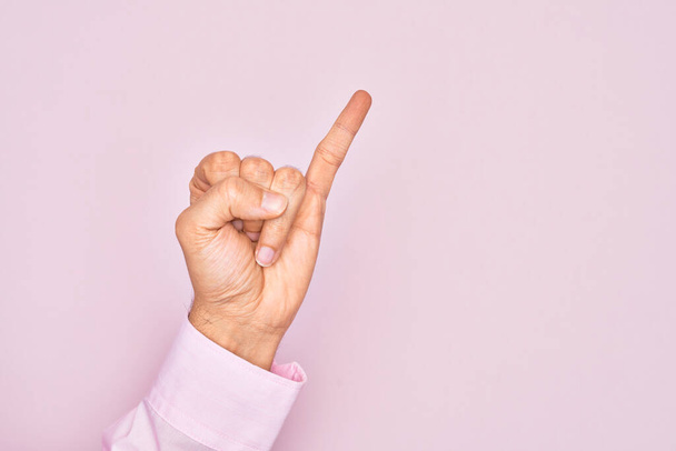 Hand van Kaukasische jongeman met vingers over geïsoleerde roze achtergrond met kleine vinger als pinky belofte inzet, nummer een - Foto, afbeelding