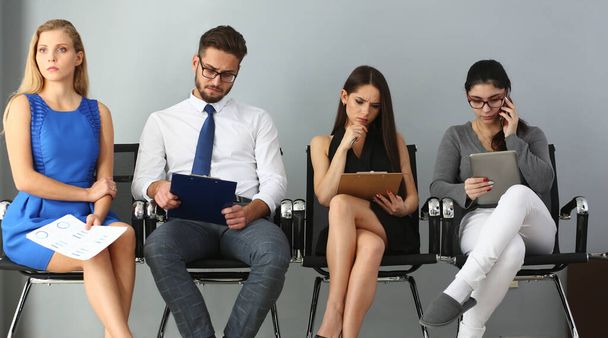 Grupo de pessoas sentadas em cadeiras durante o casting de emprego
 - Foto, Imagem