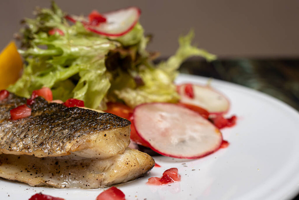 Pieczone ryby morskie z rzodkiewką warzyw, sałatą, cytryną i pomidorami. Dobre odżywianie, odchudzanie, utrzymanie zdrowia organizmu. Dieta ketonowa, dieta bezglutenowa - Zdjęcie, obraz