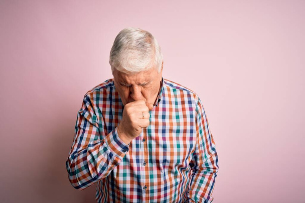 Senior pohledný chraptivý muž v ležérní barevné košili přes izolované růžové pozadí pocit nevolnosti a kašel jako symptom pro nachlazení nebo bronchitidy. Koncept zdravotní péče. - Fotografie, Obrázek