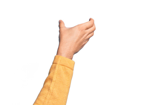 Hand of caucasian young man showing fingers over isolated white background holding invisible object, empty hand doing clipping and grabbing gesture - Photo, Image