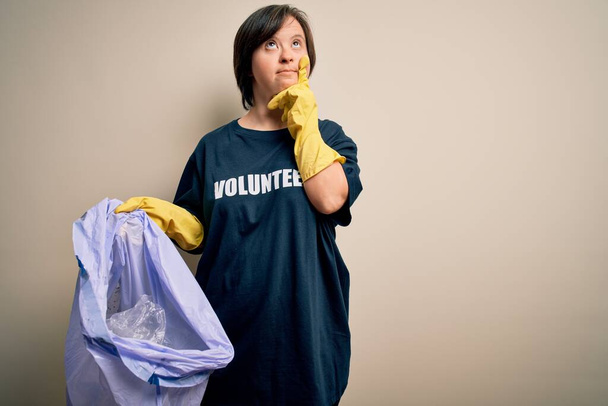 Молода вниз синдром добровольця жінка, яка збирає сміття і пластик з сміття серйозне обличчя думаючи про питання, дуже заплутана ідея
 - Фото, зображення