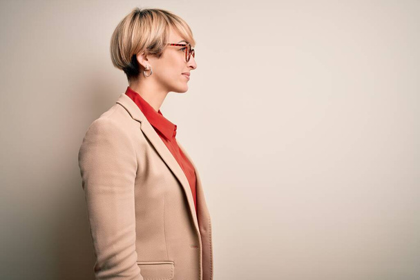 Young blonde business woman with short hair wearing glasses and elegant jacket looking to side, relax profile pose with natural face with confident smile. - Φωτογραφία, εικόνα