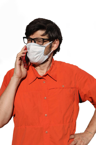 joven con máscara quirúrgica mientras llama con teléfono celular sobre fondo blanco
 - Foto, imagen