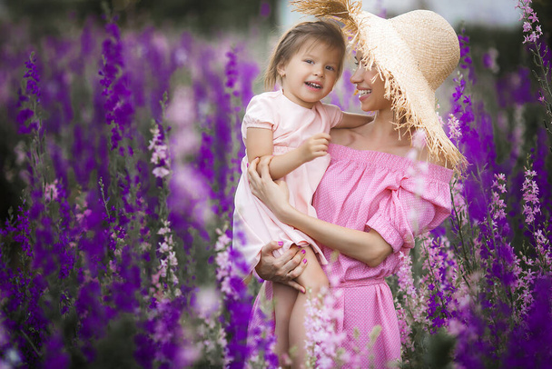 Very beautiful picture of young mother and child in the flower field - Photo, Image
