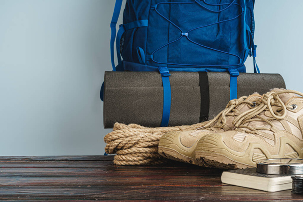 Hiking boots and rope hank on wooden board - Фото, зображення