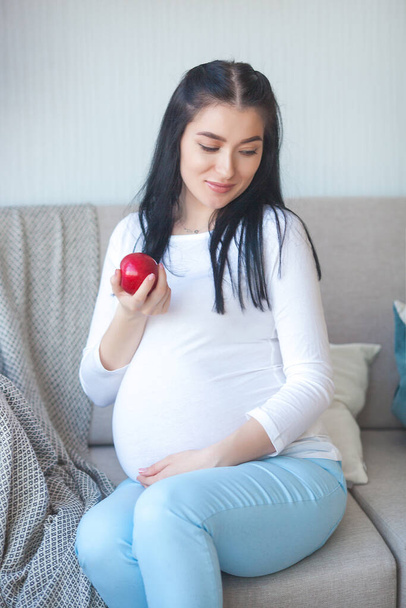Zwangere vrouw met appel. Gezondheidsconcept. Verwachtende vrouw die vers fruit eet. - Foto, afbeelding