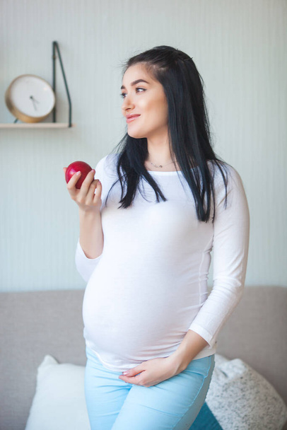 Pregnant woman holding apple. Health concept. Expecting woman eating fresh fruit. - Foto, afbeelding