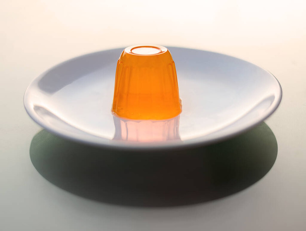 Close up of a orange gelatin on a white plate. - Foto, Imagen