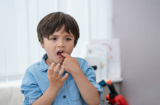 Portrait young kid putting  finger in his mounth feeling hurt from falling first tooth,Emotional child boy standing alone with thinking face or nervous, Health care or Mental health  - Foto, Imagen