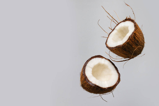 Verse rijpe kokosnoot in de lucht geïsoleerd op pastelgrijze achtergrond. - Foto, afbeelding