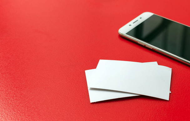 carta bianca e smartphone sul tavolo rosso. soft-focus e sopra la luce sullo sfondo - Foto, immagini