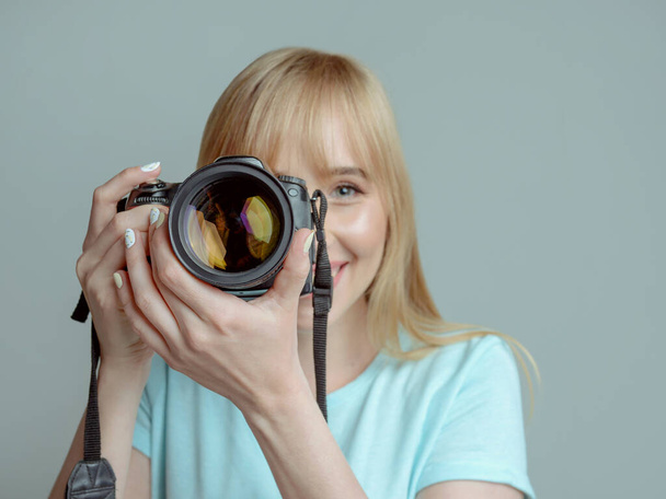блондинка стильная жизнерадостная женщина фотограф в очках с фотокамерой в руках. Озил, работа, стрельба, профессиональная концепция
 - Фото, изображение