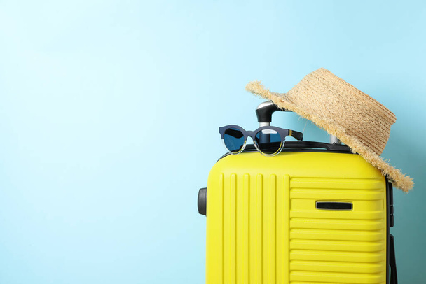 Travel bag with sunglasses and hat on blue background - Photo, Image
