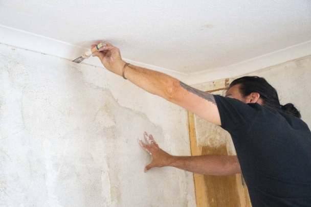 Mann saniert Wände und verputzt Risse in Wandinnenraum  - Foto, Bild