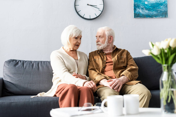 selektywne skupienie się na rozmowie pary seniorów podczas siedzenia na kanapie - Zdjęcie, obraz
