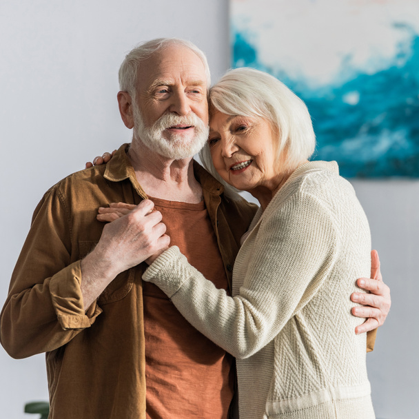 feliz pareja de ancianos sonriendo mientras bailan en casa
 - Foto, Imagen