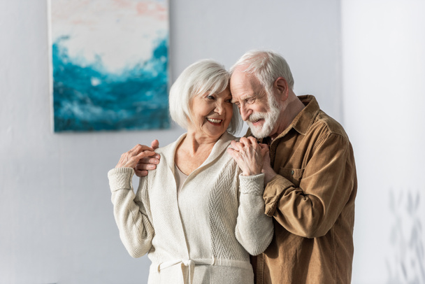 cheerful senior man touching shoulders of happy wife  - Foto, Bild