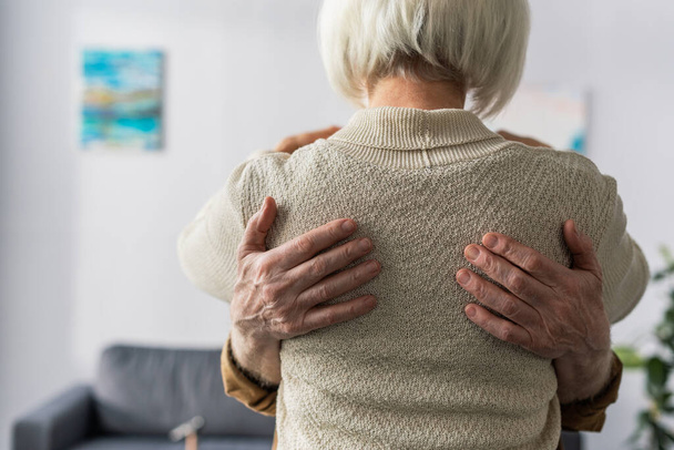 visão traseira da mulher idosa abraçada pelo marido
 - Foto, Imagem
