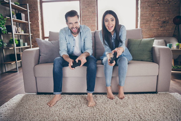 Portrait of his he her she nice attractive addicted excited glad cheerful cheery friends friendship sitting on divan playing videogame hobby at modern brick loft industrial interior house flat - Foto, Imagen