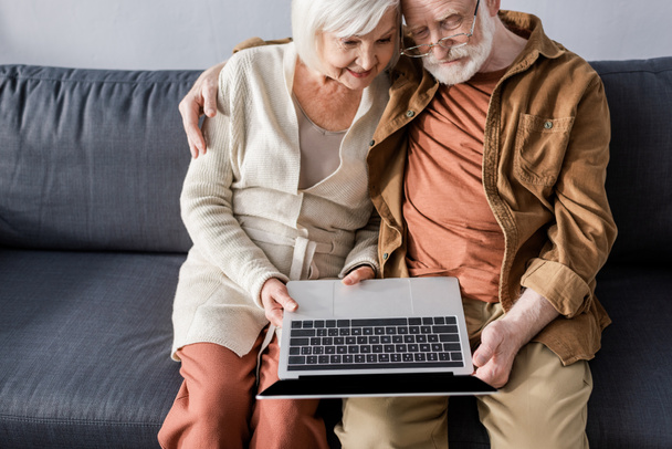 magas szög kilátás boldog idős pár ül a kanapén, és a laptop - Fotó, kép