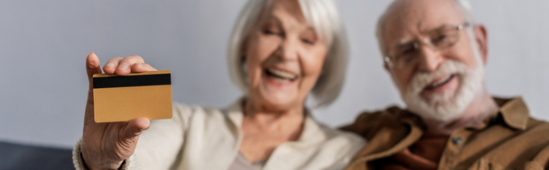valikoiva painopiste iloinen vanhempi nainen osoittaa luottokortin lähellä hymyilevä mies, verkkosivuilla otsikko - Valokuva, kuva