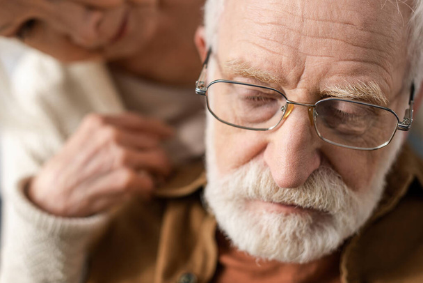 επιλεκτική εστίαση της ηλικιωμένης γυναίκας κοιτάζοντας το σύζυγο, άρρωστος στην άνοια - Φωτογραφία, εικόνα