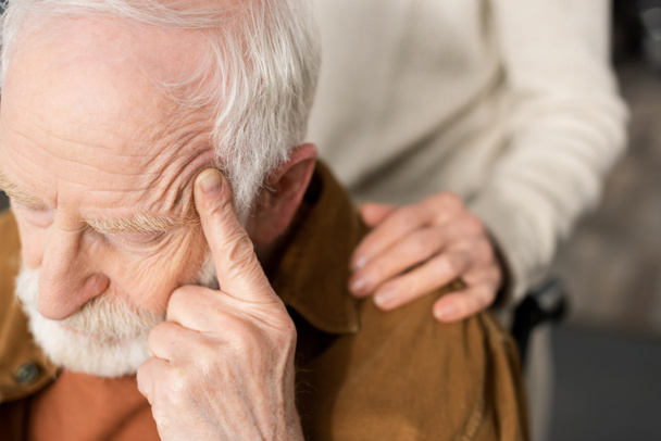 cropped view of woman touching shoulder of husband, sick on dementia, sitting with closed eyes and touching head - Photo, Image