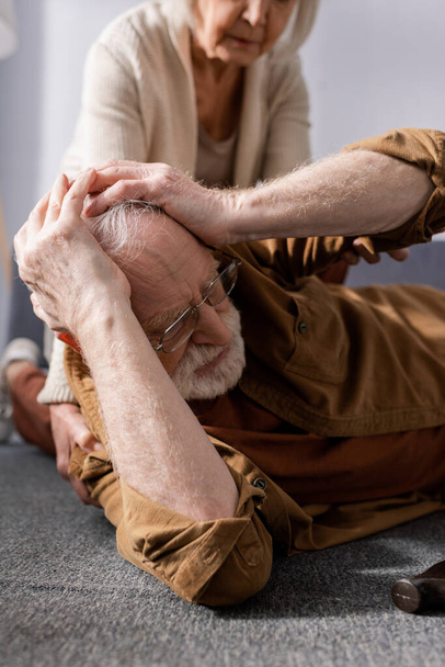 levágott kilátás idős nő közelében férj feküdt a padlón, és megérintette a fejét - Fotó, kép