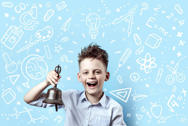 a boy in a light shirt smiles and rings a bell. Around it are various school icons on blue background - Foto, Imagen