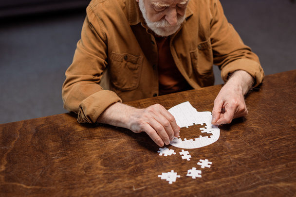 vysoký úhel pohledu na seniora muž hraje puzzle jako demence terapie - Fotografie, Obrázek
