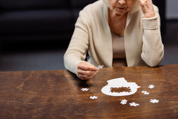 mujer mayor recogiendo rompecabezas como terapia de demencia
 - Foto, Imagen