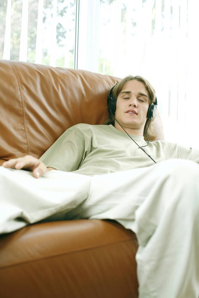 Teenage boy closing his eyes while listening to music on the headphones - Photo, image