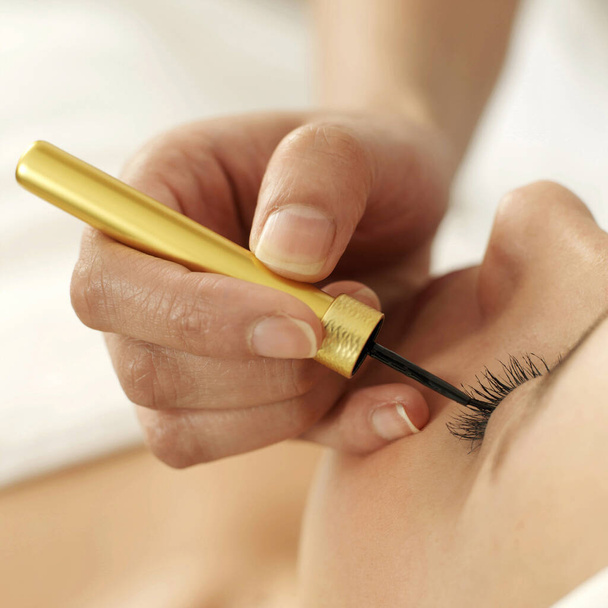 Hand applying liquid eyeliner on woman's eyelid - Foto, Imagem