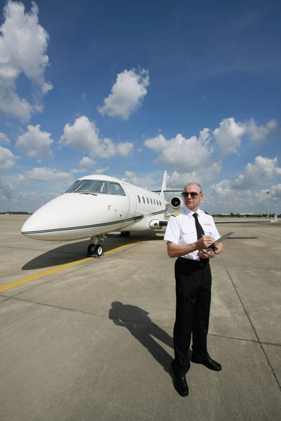Pilot standing at runway holding a clipboard - Valokuva, kuva