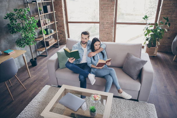 Top above high angle view full length photo of concentrated woman man lie couch hug embrace read interesting paper book in house indoors - Foto, imagen