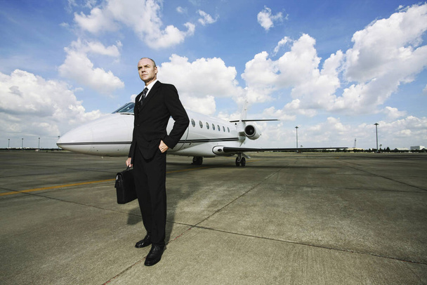 Businessman standing at private jet runway - Фото, зображення