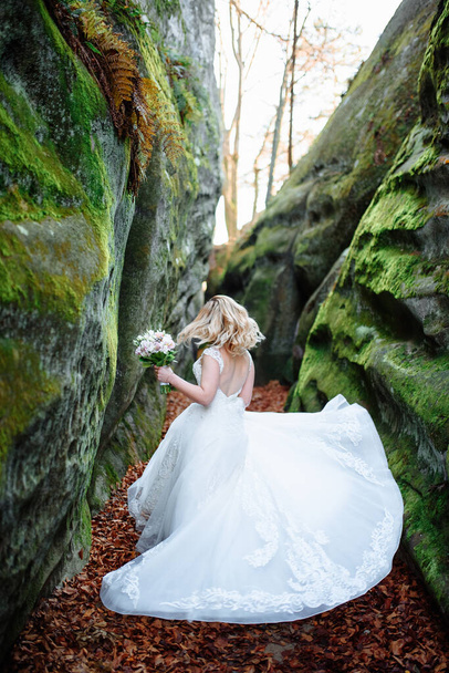 Beautiful blonde bride is spinning in a narrow gorge. - Fotoğraf, Görsel