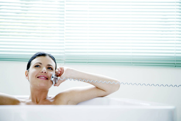 Woman talking on the mobile phone while sitting in the bathtub - Valokuva, kuva