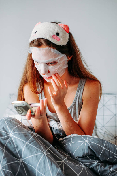 Procedimentos internos de beleza em casa. Mulher usando máscara de dormir e máscara hidratante se preparando pela manhã
. - Foto, Imagem