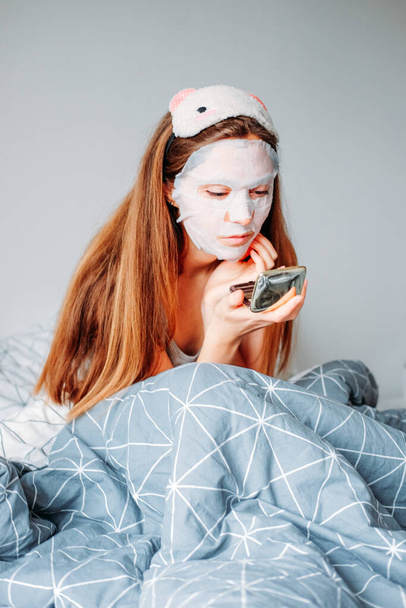 Indoor home beauty procedures. Woman wearing sleeping mask and moisturizing mask getting ready in the morning. - Photo, Image