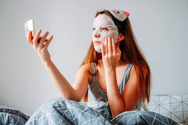 Εσωτερικές διαδικασίες ομορφιάς. Γυναίκα με μάσκα ύπνου και ενυδατική μάσκα ετοιμάζεται το πρωί. - Φωτογραφία, εικόνα