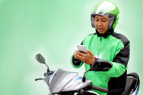 motociclista procurando smartphone para táxi online. Yogyakarta Indonésia. 30 de março de 2020
 - Foto, Imagem