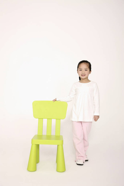Girl standing next to a green chair - Фото, изображение