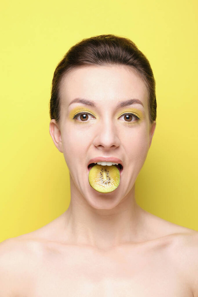 Woman with a slice of kiwi on her tongue - Φωτογραφία, εικόνα
