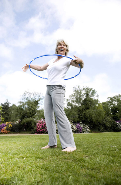 Senior woman playing with plastic hoop in the park - Fotoğraf, Görsel