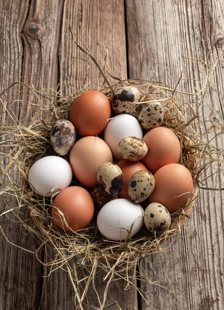 Uova di gallina e quaglia in fieno in un cesto - Foto, immagini