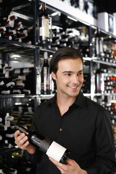 Man choosing a bottle of wine from the wine cellar - Foto, afbeelding